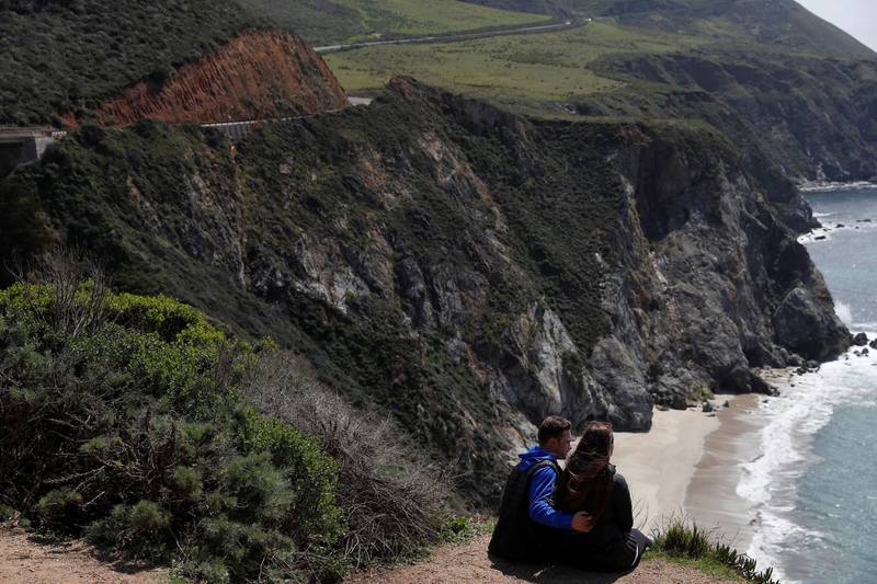 A couple sits on a cliff area next to State Route 1 along the Pacific coastline outside go Big Sur, California. Reuters