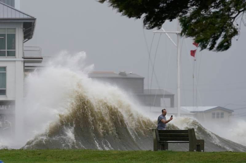 A man takes pictures of high waves along the shore of Lake Pontchartrain. AP