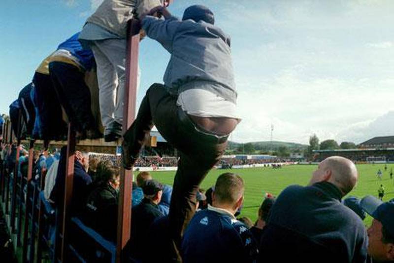 Manchester City fans climb to get a better vantage point at Macclesfield's Moss Rose ground, during a Division Two match in 1998.