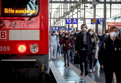 Commuters wearing face masks walk on a platform in the main train station in Frankfurt, Germany. AP Photo