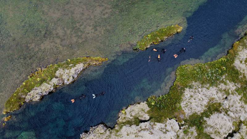 An aerial view shows snorkellers in the main Silfra fissure which is approximately 300 meters long, on July 26, 2022 in Thingvellir, Iceland.  - In between North American and Eurasian tectonic plates, Iceland's Silfra fissure is one of the world's most famous dive sites, popular with tourists who venture into its icy waters.  (Photo by Jeremie RICHARD  /  AFP)  /  TO GO WITH AFP STORY BY JEREMIE RICHARD