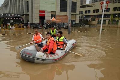 Rescue workers paddle through a flooded street following heavy rain that caused flooding in the city of Zhengzhou in China's Henan province.