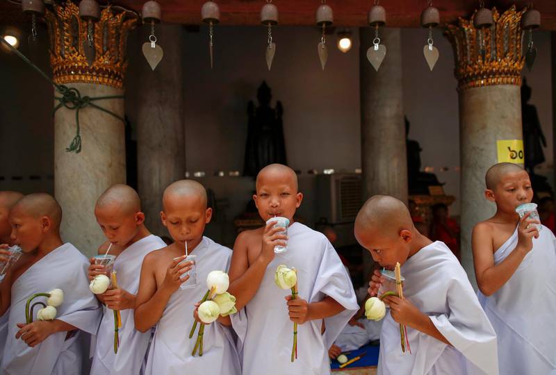 Newly ordained novice monks sip water during a mass Buddhist monk ordination ceremony for hill tribe men at Wat Benchamabophit, also known as the Marble Temple in Bangkok, Thailand. EPA