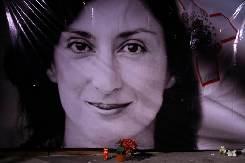 Flowers and a candle lie in front of a portrait of assassinated investigative journalist Daphne Caruana Galizia during a vigil outside the law courts in Valletta, Malta. AP