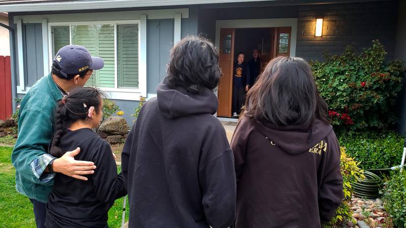 This March 2020 photo provided by Graciela TiscareÃ±o-Sato of Castro Valley, Calif., shows her with her husband and children, foreground, singing to her mother-in-law for her 79th birthday at a safe distance due to the COVID-19 coronavirus outbreak. "Imagine now trying to explain to your child why she can't hug her grandmother," she says. "You're very much missing the human contact when you're standing 30 feet away." (Courtesy Graciela TiscareÃ±o-Sato via AP)