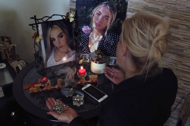 Chouchan Yeghiyan prays in front of pictures of her daughter, Jessica Bezdjian, who was killed in last year's blast at Beirut port.