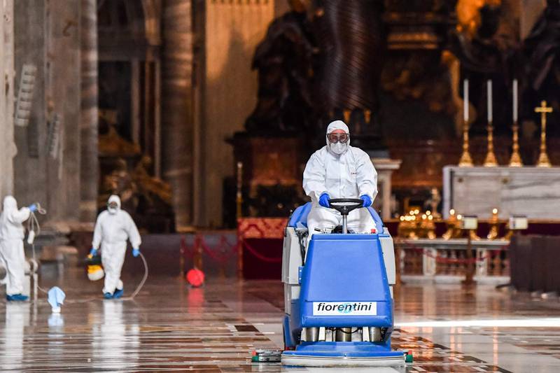Men wearing protective overalls and mask sanitise St Peter's Basilica in The Vatican. AFP