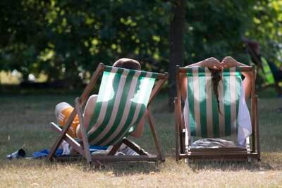 A couple relax on deckchairs in the hot weather in Hyde Park, London, in 2014. 