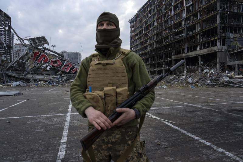 A soldier poses for the picture in Kyiv, Ukraine, while standing guard amid the destruction caused after shelling of a shopping center. AP Photo