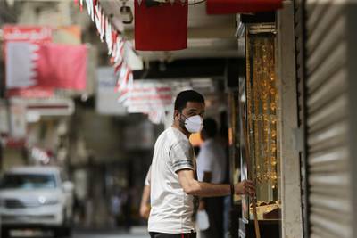 A man wearing a protective face mask stands in front of his gold jewellery shop in a street of Manama. EPA