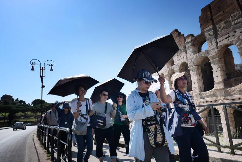 Tourists shelter from the sun with umbrellas in front of the Colosseum in Rome during a heatwave.  Meteorologists blamed a blast of torrid air from the Sahara for the unusually early summer heatwave, which could send thermometers up to 40 degrees Celsius (104 Fahrenheit) across large swathes of the continent. AFP