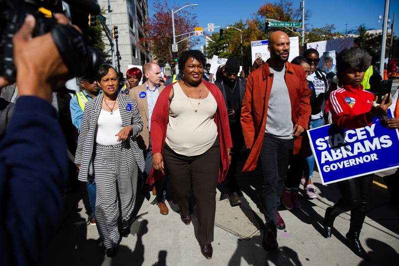 Ms Abrams and rapper Common lead a 'Souls to the Polls' march in Atlanta. Bloomberg