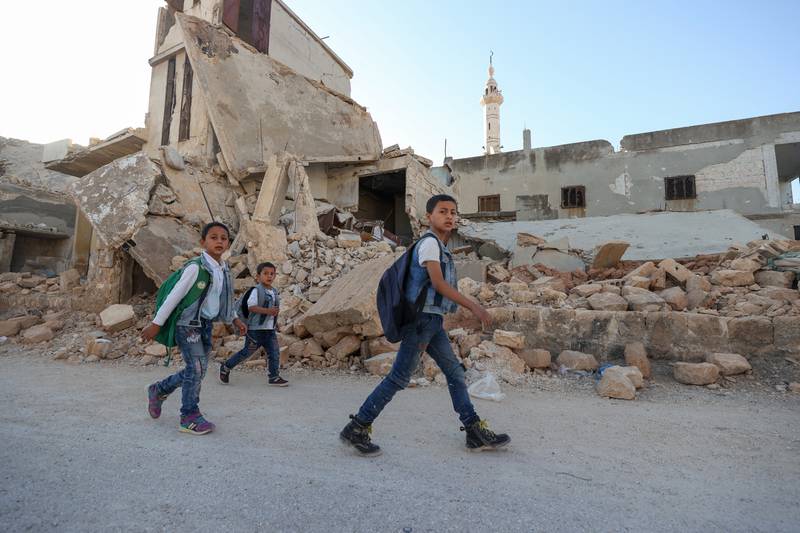 Children walk among the rubble as they attend the first day of school in a village in the countryside of Syria's northwestern Idlib province.