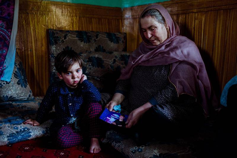 January 25th, 2019 - Kabul, Kabul, Afghanistan: Fawzia, Tooryalai's mother, displays a photo of Tooryalai in a room at their home as his son Kawsar sits nearby.

Tooryalai died of his wounds following the attack on the Green Village, a compound in Kabul that houses foreign workers and NGO's, initially killed 9 and wounded over 120 Afghans who lived in the vicinity.

He is survived by his wife and three children. The children do not know that he is dead.

Ivan Flores/The National