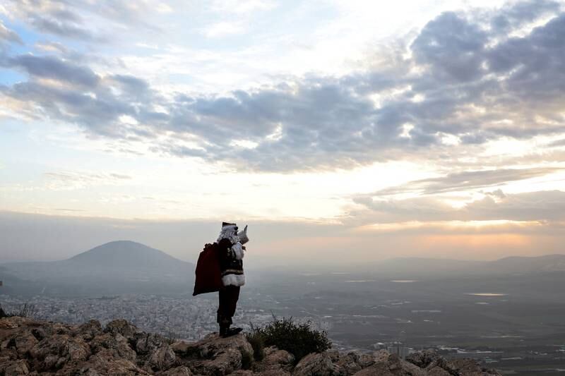 Issa Kassissieh, dressed as Santa Claus, waves and poses for members of the media as he stands on Mount Precipice in front of Mount Tabor close to Nazareth in northern Israel. Reuters