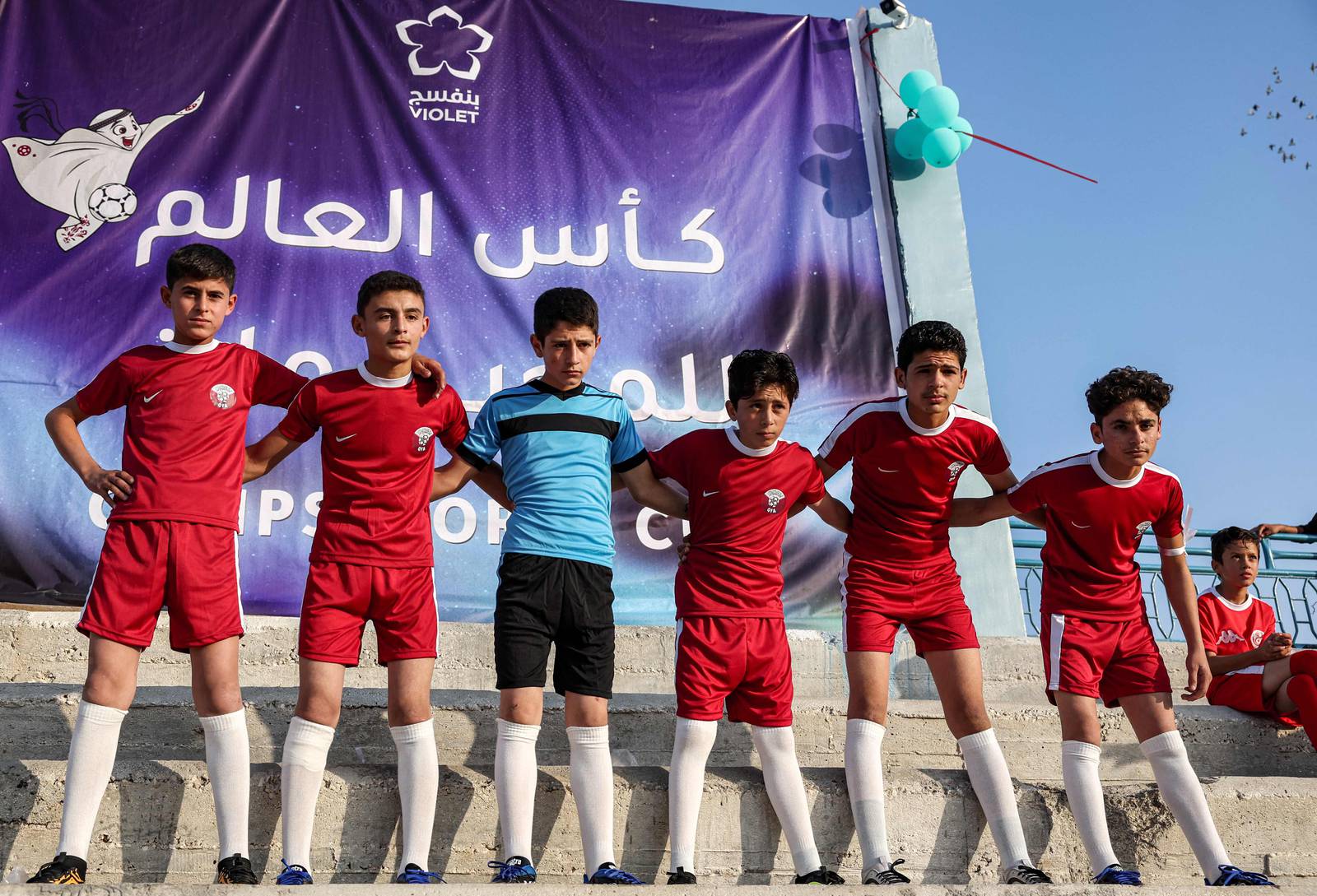Des enfants portant des bandes qataries posent pour une photo lors de la cérémonie d'ouverture de la Coupe du monde des camps à Idlib.