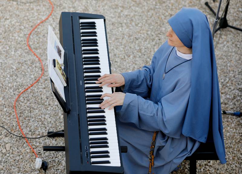 A nun plays music during a baptism.