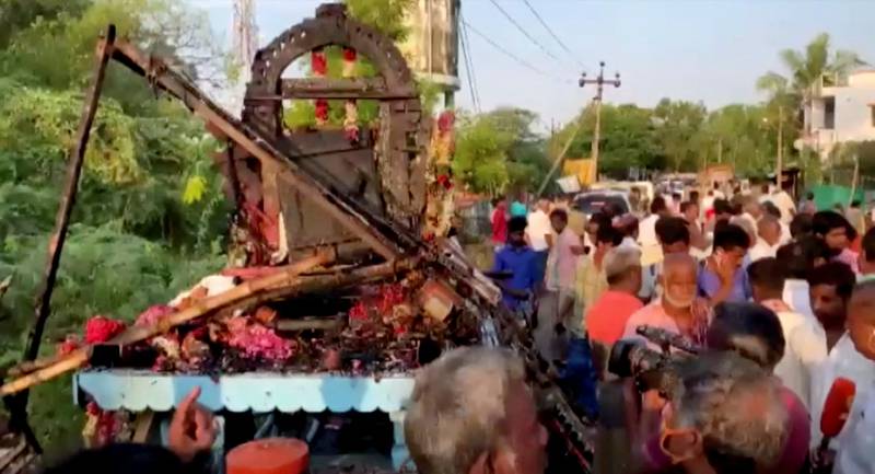 People gather around a chariot that was damaged after a high voltage power wire fell on it, killing at least 11 people, during a procession in a temple festival in Kalimedu village, Thanjavur district, India April 27, 2022 still image obtained from video. Reuters
