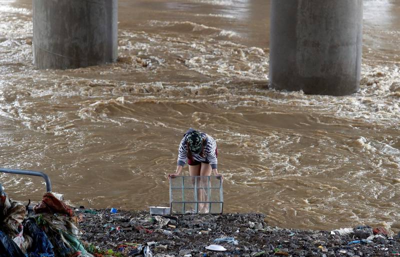 A woman cleans a glass cabinet near floodwaters in Marikina, Metro Manila. Reuters