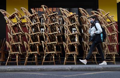 A pedestrian walks past a closed cafe terrace with chairs stacked outside in Paris, France. EPA