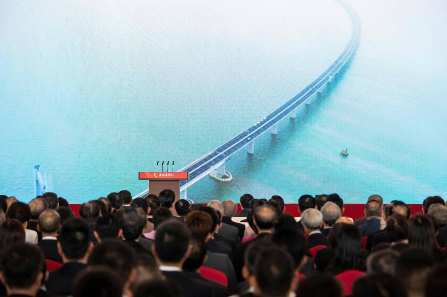 Guests and politics watch a trailer on a giant screen during the opening ceremony of the Hong Kong-Zhuhai-Macau Bridge at the Zhuhai Port terminal on October 23, 2018. China's President Xi Jinping launched the world's longest sea bridge connecting Hong Kong, Macau and mainland China on October 23 at a time when Beijing is tightening its grip on its semi-autonomous territories. / AFP / FRED DUFOUR
