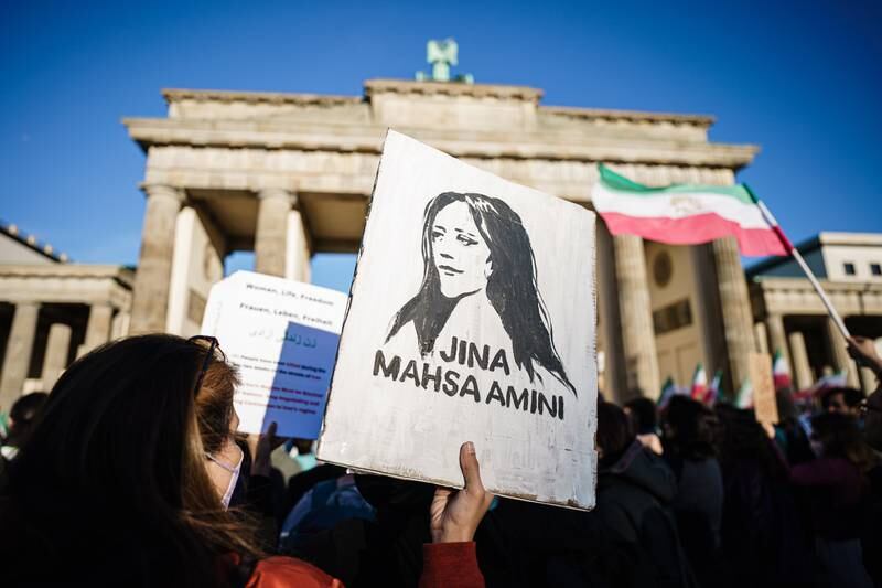 A protester holds a painted portrait of Mahsa Amini in Berlin, Germany. EPA