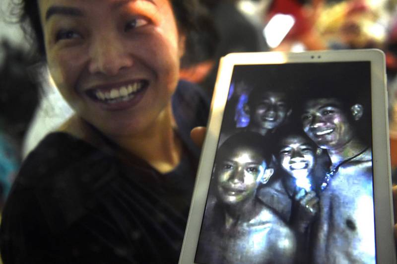 A happy family member shows the latest picture of the missing boys taken by rescue divers inside Tham Luang cave  when all members of children's football team and their coach were found alive in the cave at Khun Nam Nang Non Forest Park in the Mae Sai district of Chiang Rai province late July 2, 2018. Lillian Suwanrumpha / AFP