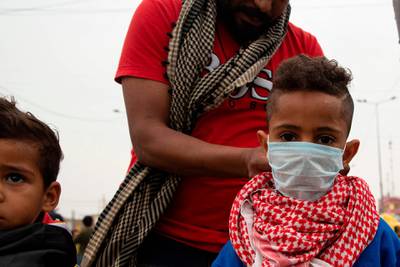 An anti-government demonstrator adjusts a protective mask on a child's face in Basra, Iraq.  AFP