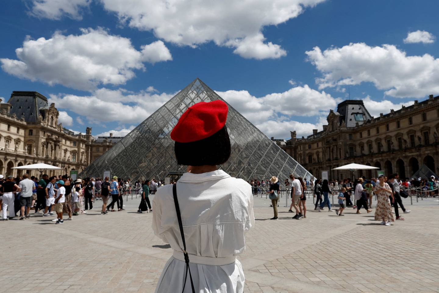 A tourist takes photographs of the Louvre Museum in Paris. Reuters