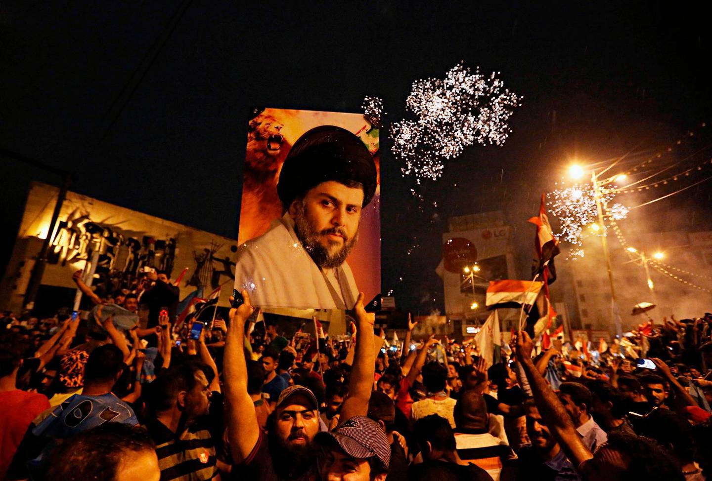 FILE - In this Monday, May 14, 2018 file photo, supporters of Shiite cleric Muqtada al-Sadr, carry his image as they celebrate in Tahrir Square, Baghdad, Iraq. Al-Sadr, who led punishing attacks on American forces after the 2003 U.S.-led overthrow of Saddam Hussein, appears set to secure the most significant victory of his political career with a strong showing in the May 12 parliamentary election. Al-Sadr gained popularity as a nationalist voice campaigning against corruption and against Iranâ€™s influence in the country. (AP Photo/Hadi Mizban)