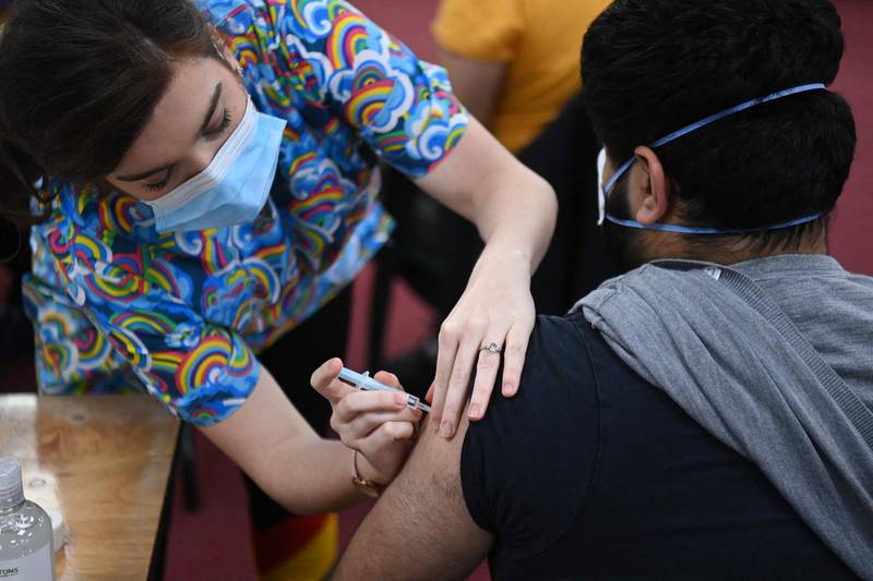 A health worker administers a dose of the AstraZeneca/Oxford vaccine at a coronavirus vaccination centre at the Fazl Mosque in southwest London on March 23, 2021, on the first anniversary of the first national Covid-19 lockdown.  / AFP / DANIEL LEAL-OLIVAS
