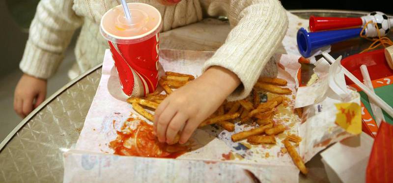 A child eats chips soaked in tomato sauce with a large fizzy drink at an Abu Dhabi fast food outlet. Sammy Dallal / The National