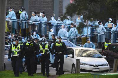 Victoria Police officers and healthcare workers congregate outside a public housing tower in North Melbourne, Australia. Nine towers in Flemington and North Melbourne were locked down on Saturday in an effort to slow the spread of coronavirus.  EPA