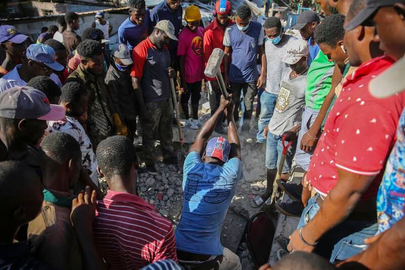 A man uses a sledgehammer to rescue people from the rubble of a destroyed home in Les Cayes after the earthquake struck Haiti in August 2021. AP