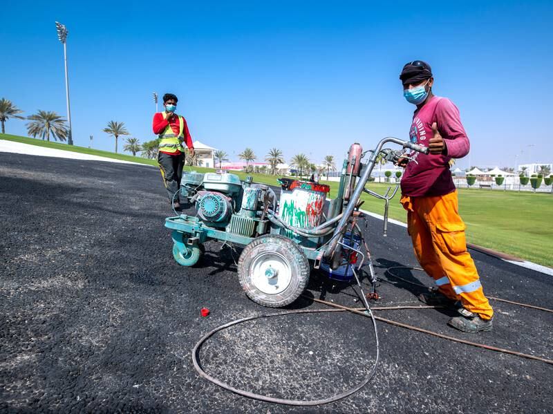 Workers apply paint to the tarmac. Victor Besa / The National