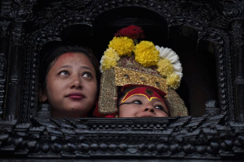 Living god Ganesh looks out from a window during the annual Indra Jatra festival in Kathmandu, Nepal, Friday, Sept.  9, 2022.  The girl child revered as the living goddess was pulled around the main parts of the capital Friday by devotees on a wooden chariot as tens of thousands of people lined up the old city to get a glimpse and blessing.  (AP Photo / Niranjan Shrestha)