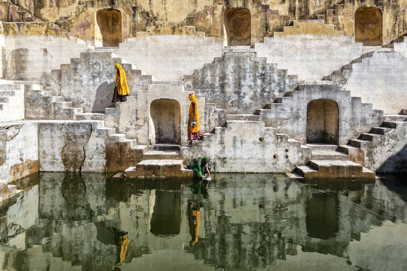 "Women in saris carrying water at step well, Jaipur, Rajasthan, India"