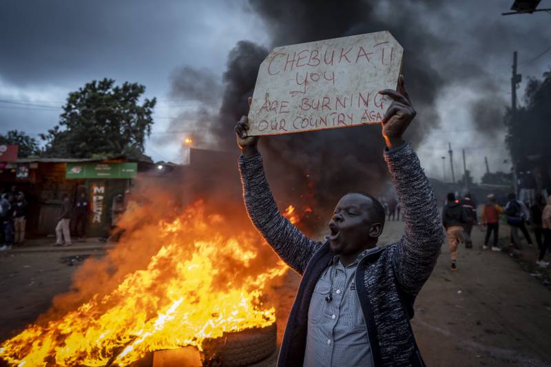 A supporter of presidential candidate Raila Odinga holds a placard referring to electoral commission chairman Wafula Chebukati, while shouting "No Raila, No Peace", in Kibera. AP