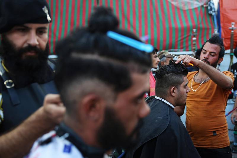 Demonstrators cut each other's hair as they take part in ongoing anti-government protests, in Baghdad. Reuters