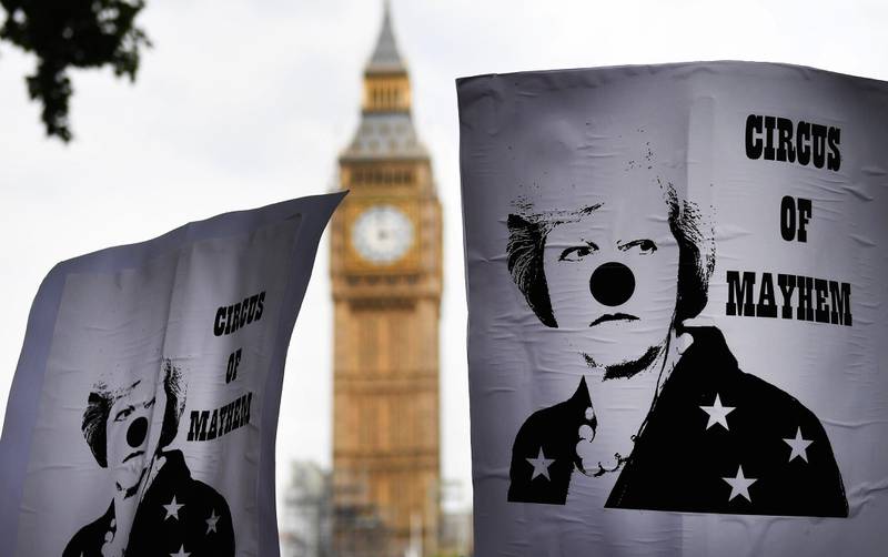epaselect epa06060070 People hold placards with british Prime Minister Theresa May dressed as a clown and sign reading 'Circus of Mayhem' as they take part in an anti-austerity demonstration outside Parliament in London, Britain, 01 July 2017. Tens of thousands of people took part in a demonstration against British Government and called to end austerity, further cuts and privatisation.  EPA/ANDY RAIN