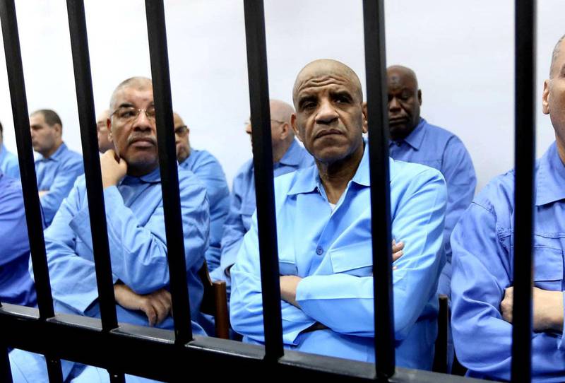 Former Libyan intelligence chief Abdullah al-Senussi (front row 2R) sits dressed in prison blues with other defendants behind the bars of the accused cell during a hearing as part of their trial on April 20, 2015 at court of appeals in the Libyan capital, Tripoli. Thirty-seven former officials of slain Libyan dictator Moamer Kadhafi are charged with murder, kidnapping, complicity in incitement to rape, plunder, sabotage, embezzlement of public funds and acts harmful to national unity. AFP PHOTO / MAHMUD TURKIA (Photo by MAHMUD TURKIA / AFP)