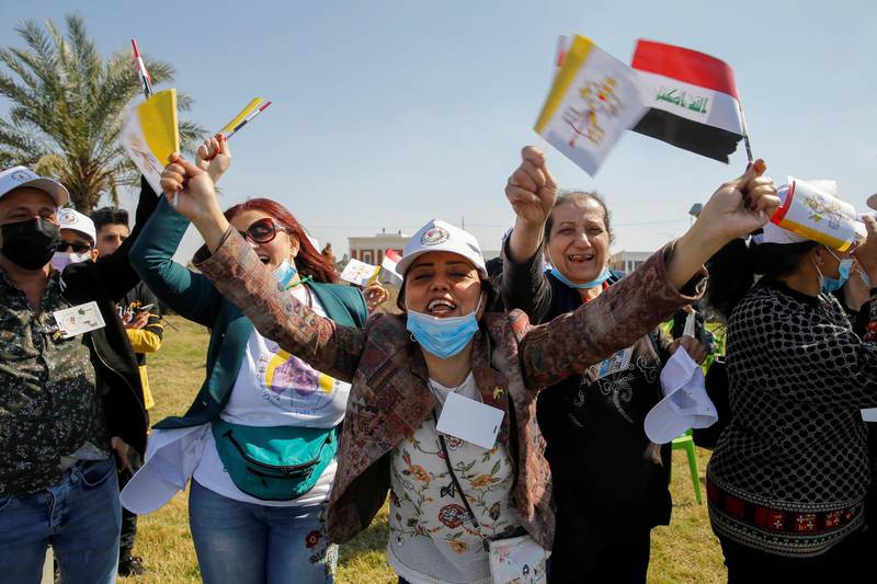 People holding Iraqi and Vatican flags as they wait for the arrival of Pope Francis, at Baghdad Airport Road, in Baghdad, Iraq. Reuters