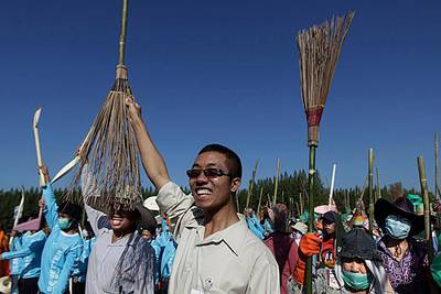 City workers, volunteers raise their brooms and spades as they shout slogans before starting a cleaning operation in Patum Thani on the outskirts of Bangkok, Thailand, Tuesday, Nov. 22, 2011. The situation has improved dramatically in recent days and cleanup has begun in many areas, though some still face weeks more under water. (AP Photo/Altaf Qadri)