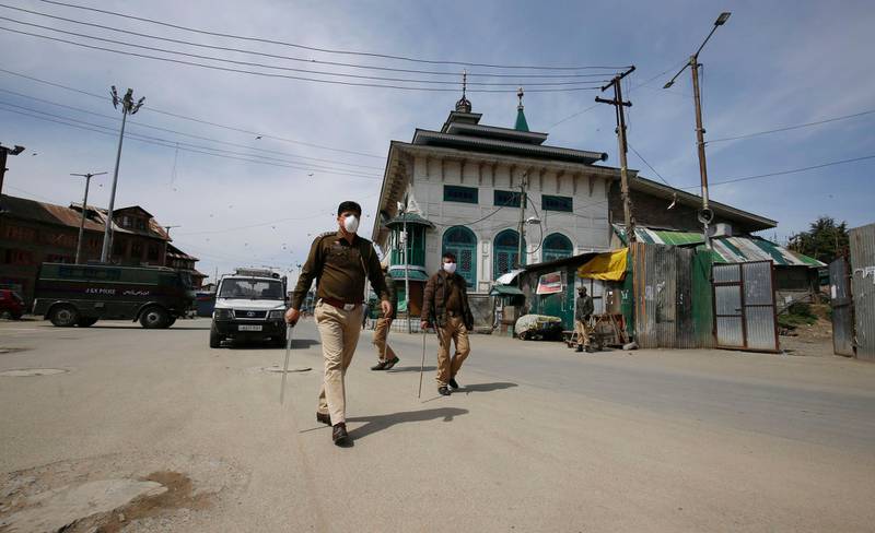 Indian policemen stand guard outside a shrine during a lockdown in Srinagar. EPA