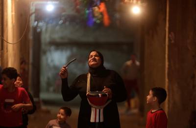 Children are seen as Hajja Dalal, a 46-year-old Mesaharati, beats a drum to wake up Muslims to have the predawn meal before they start their long-day fast in Cairo, Egypt. Reuters