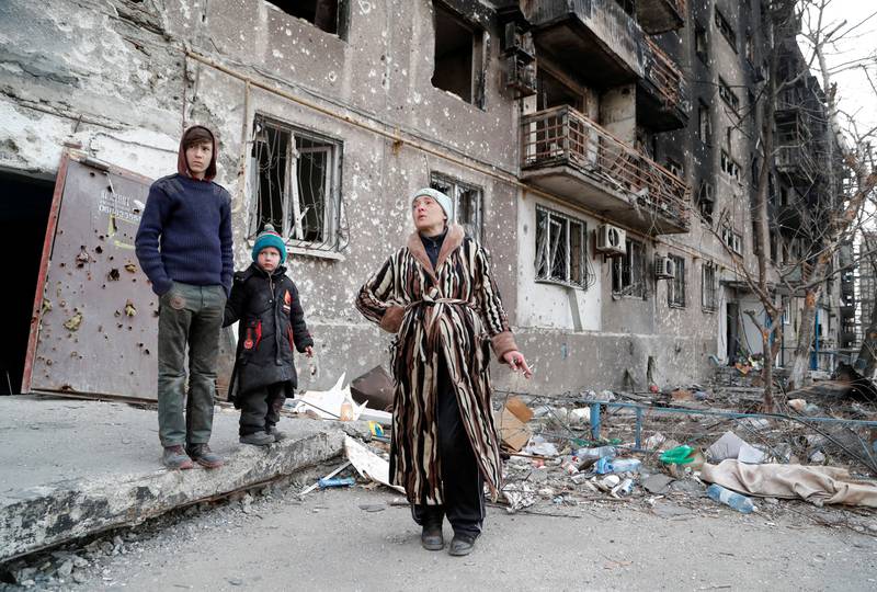 Family members, seeking refuge in abandoned apartments of a residential building damaged in the course of Ukraine-Russia conflict, gather in a courtyard in Mariupol. Reuters
