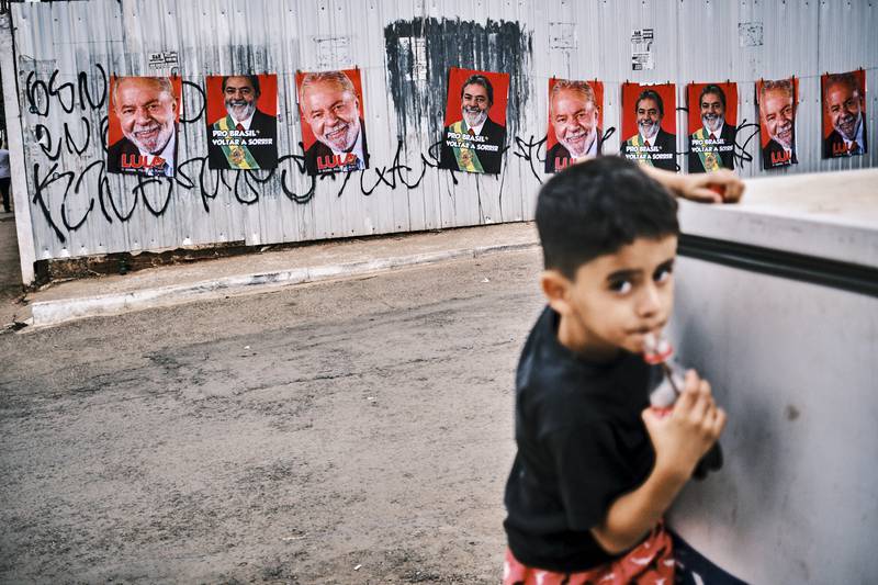 A child drinks a bottle of cola near a wall displaying images of presidential candidate Luiz Inacio Lula da Silva, in Brasilia. Brazilians will go to polls on October 2. Getty Images