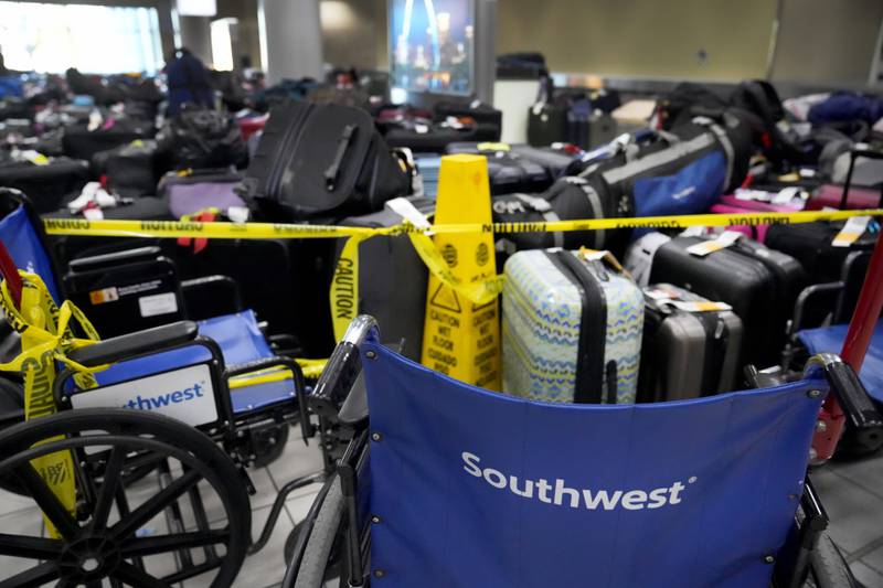 Wheelchairs and suitcases sit behind yellow caution tape as Southwest travellers deal with cancelled flights. AP