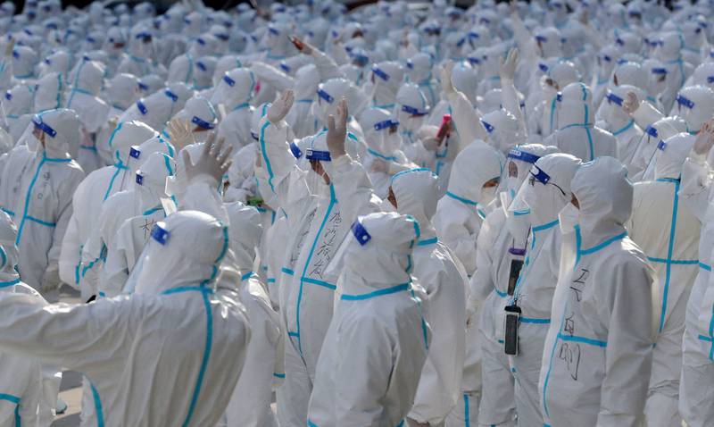 Medical workers in protective suits wave at Changchun residents during a farewell ceremony before returning to Meihekou, where they were sent from to help curb the Covid-19 outbreak in Jilin province, China. Reuters