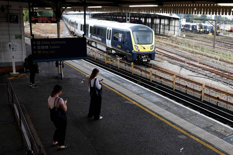 Commuters wait on a platform at Clapham Junction in London. AFP
